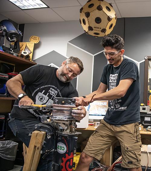 A student and staff member work on an electric motor in the makerspace